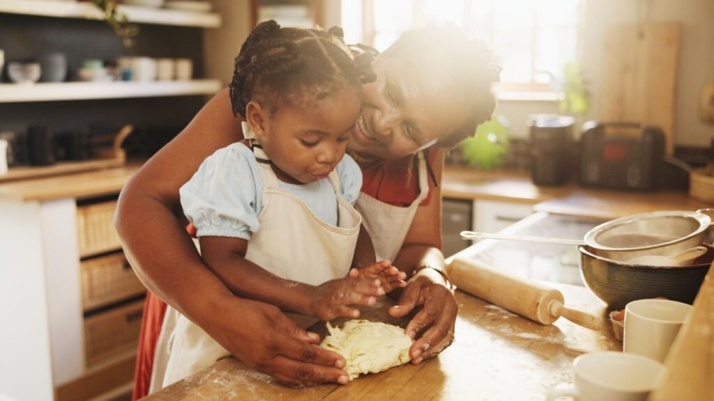 Black woman, child and teaching with dough, cooking and nutrition for support, love and education. Grandmother, girl and baking for development, growth and kitchen as happy family in bonding in home