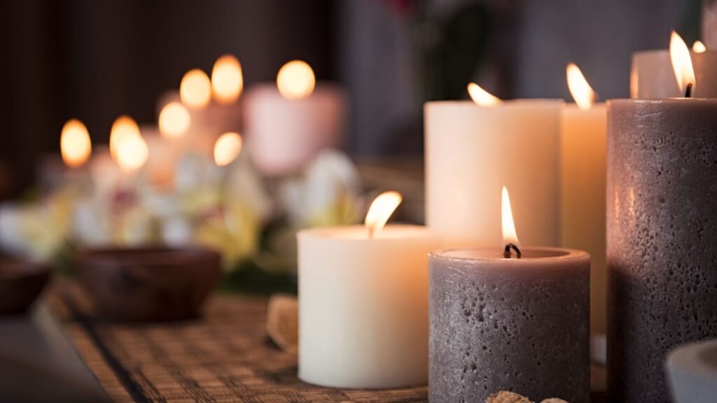 Closeup of burning candles spreading aroma on table in a spa room. Beautiful composition with grey and white candles for spa treatment. Zen and relax concept.