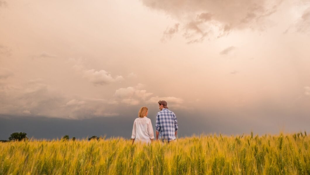 Couple in a field of wheat amid dramatic stormy sky
