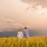Couple in a field of wheat amid dramatic stormy sky