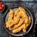 Crispy chicken tenders strips with Ketchup. Black background. Top view.