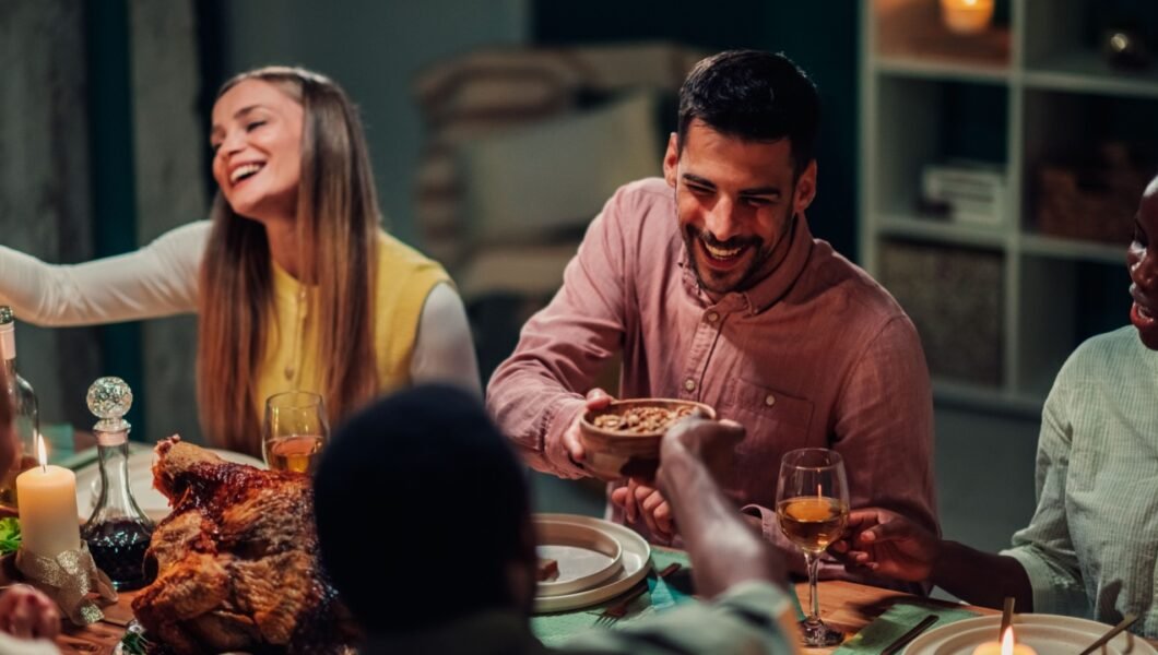 Happy friends sharing a festive thanksgiving dinner, laughing and enjoying delicious food while celebrating together in a warm, cozy atmosphere