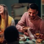 Happy friends sharing a festive thanksgiving dinner, laughing and enjoying delicious food while celebrating together in a warm, cozy atmosphere