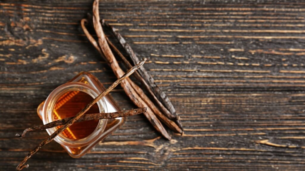 Jar with vanilla extract and sticks on wooden table