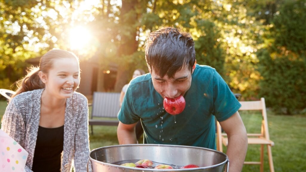 Teenage boy, apple in mouth, apple bobbing at garden party