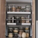 Variety of dry foods, grains, nuts, cereals in glass jars in kitchen cupboard. Zero waste storage concept.