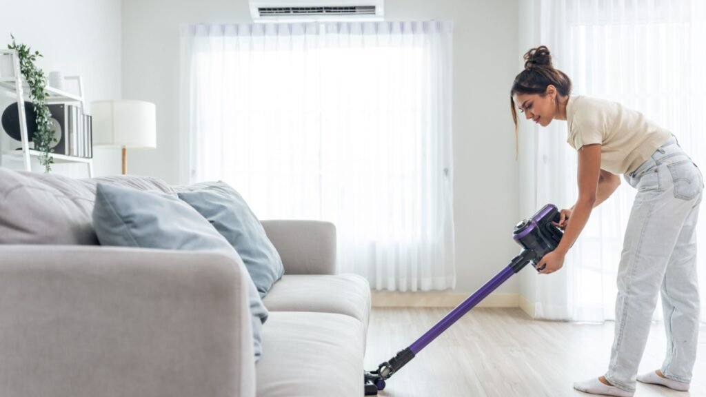 young beautiful woman cleaning indoors living room at home.chores in house
