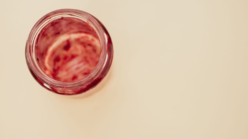 A top view of an empty strawberry jam jaisolated on light brown background