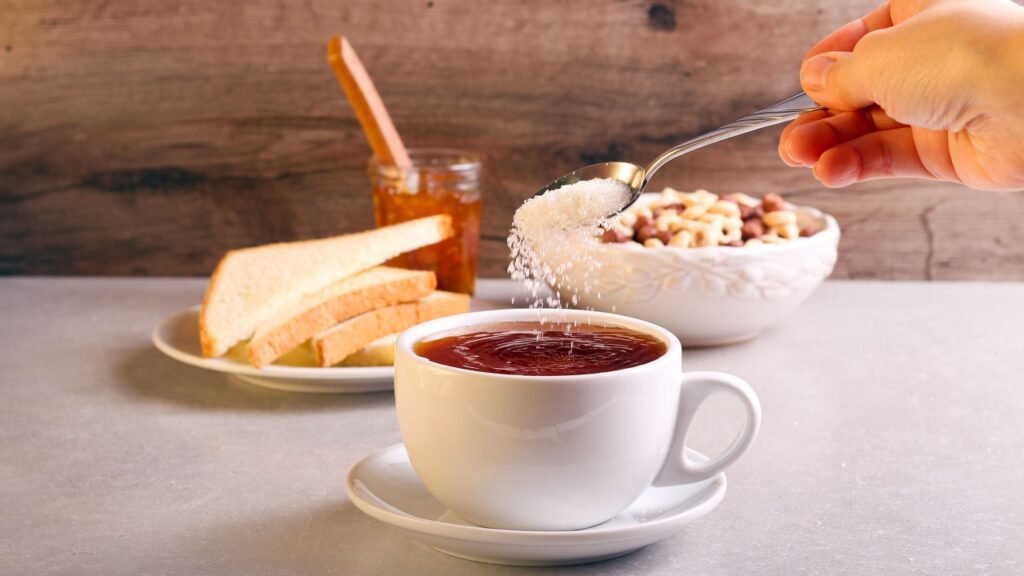 Adding sugar into tea in a cup, selective focus
