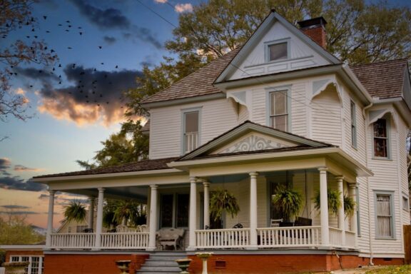 An old farmhouse with house plants on the front porch