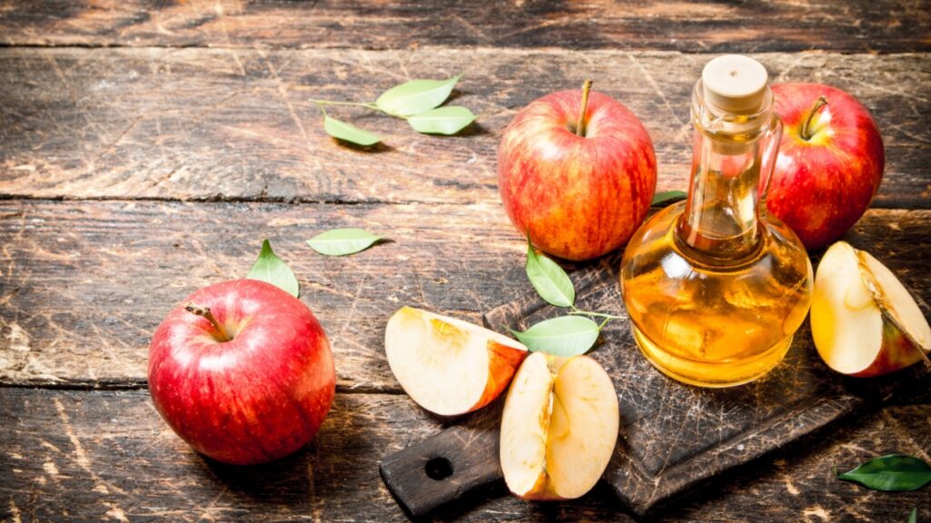 Apple cider vinegar, red apples . On wooden background.