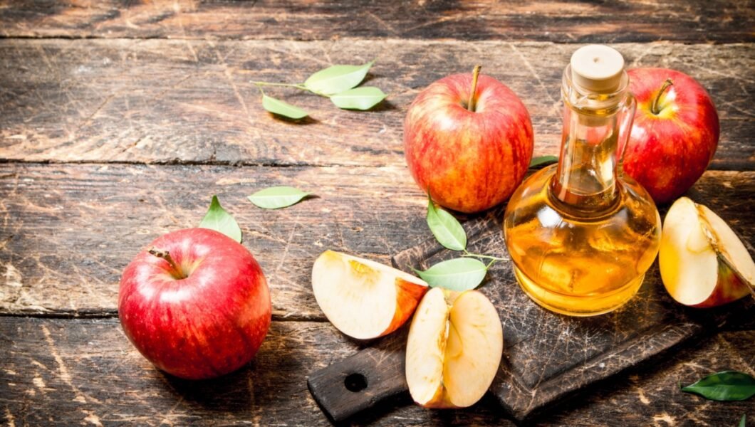 Apple cider vinegar, red apples . On wooden background.