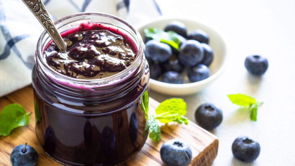 Blueberry jam in the glass jar with fresh berries.