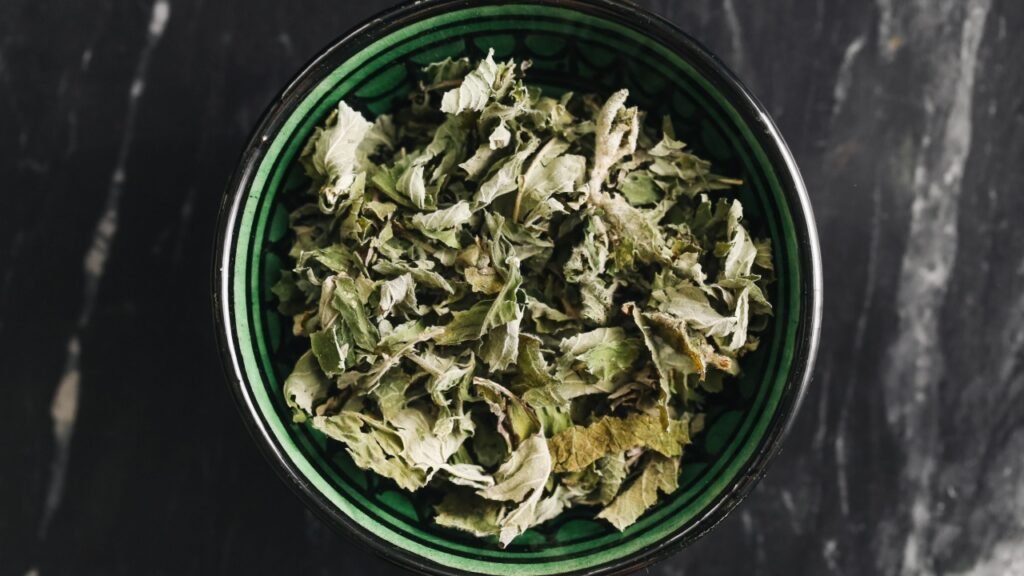 Dried mint leaves in bowl. Herbal tea ingredient. Aromatic natural remedy. Healthy traditional drink. Fresh green texture. Organic herbal infusion. Natural wellness. Rustic kitchen background style.