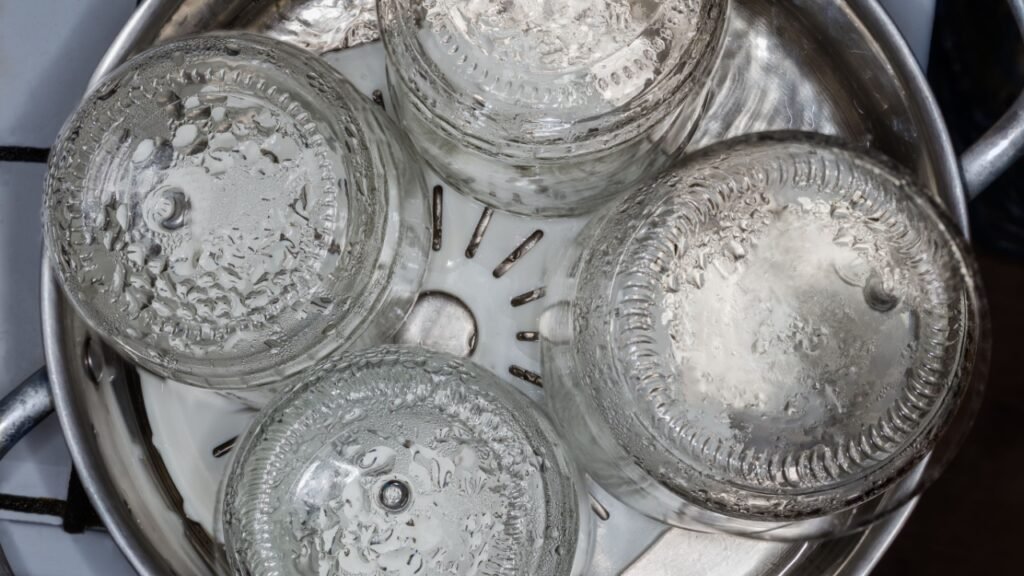 Glass jars in the stainless steel pot over the steamer during steam sterilization for the home canning, top view