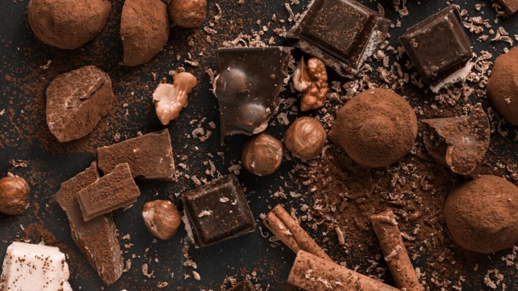 Variety of sweet homemade chocolate pralines on wooden background. New trending PANTONE 17-1230 Mocha Mousse colour of 2025 year 
