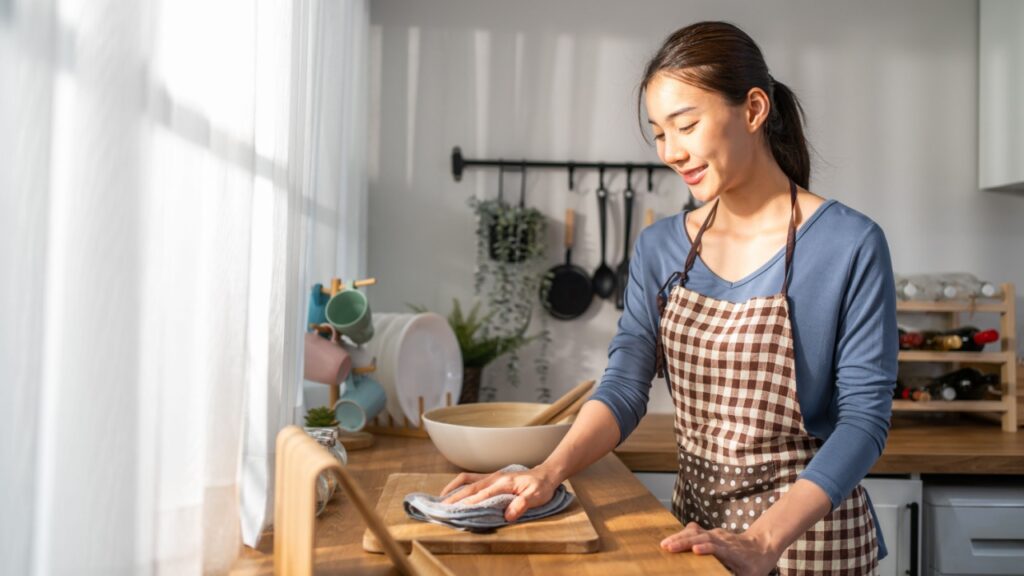 Asian beautiful cleaning service woman worker cleaning kitchen at home. Beautiful girl housewife housekeeper cleaner feel happy and wiping messy dirty dining table for housekeeping housework or chores